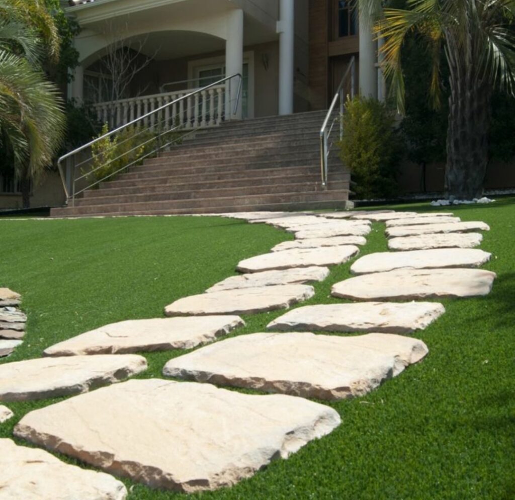 Camino de piedra natural integrado en césped artificial en un jardín de Gran Canaria