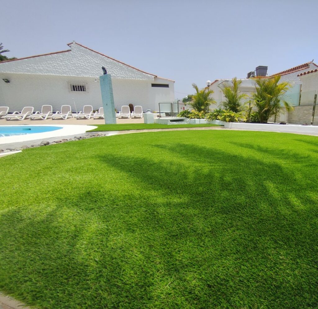 Zona de piscina con tumbonas sobre césped artificial en Las Palmas