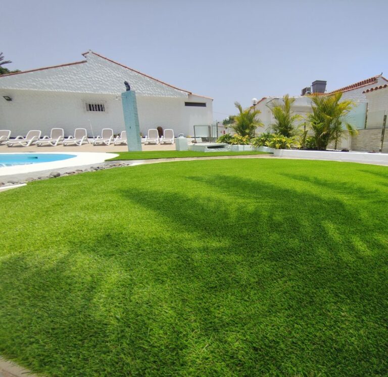 Zona de piscina con tumbonas sobre césped artificial en Las Palmas